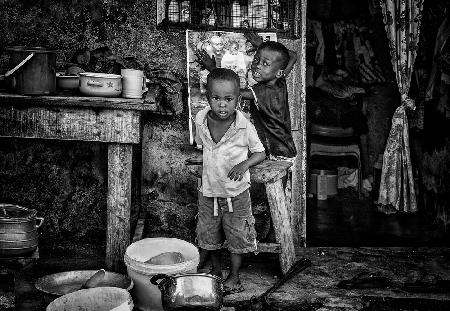 Zwei Kinder hängen ein Plakat in den Straßen von Accra-Ghana auf